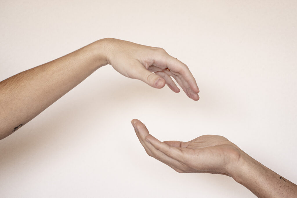 Dos manos que se buscan sobre fondo neutro, símbolo del cuerpo que expresa lo que se calla en el síndrome de la niña buena